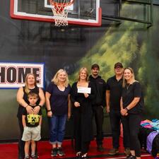 Group photo of staff and volunteers holding a cheque at a community event
