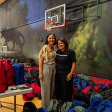 Two female staff standing with filled backpacks waiting to hand out to students