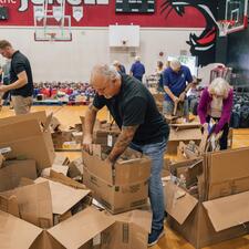 Male staff surrounded by empty boxes as he breaks them down for recycling