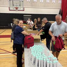 Volunteers at a line of tables filling backpacks with supplies