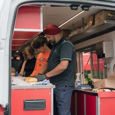 Volunteers in the back of a van preparing hot dogs to be handed out to community members